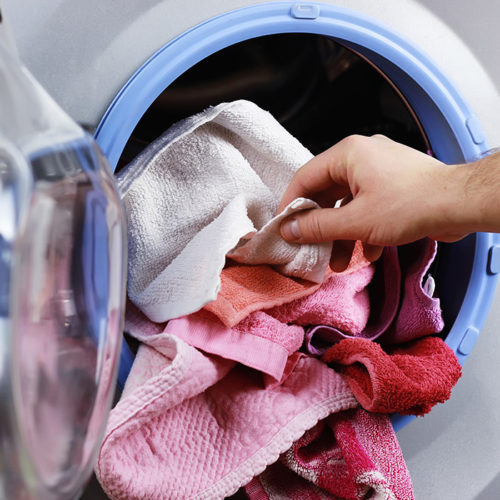 man-hand-close-up-adding-towels-to-dryer-machine-fort-collins-co